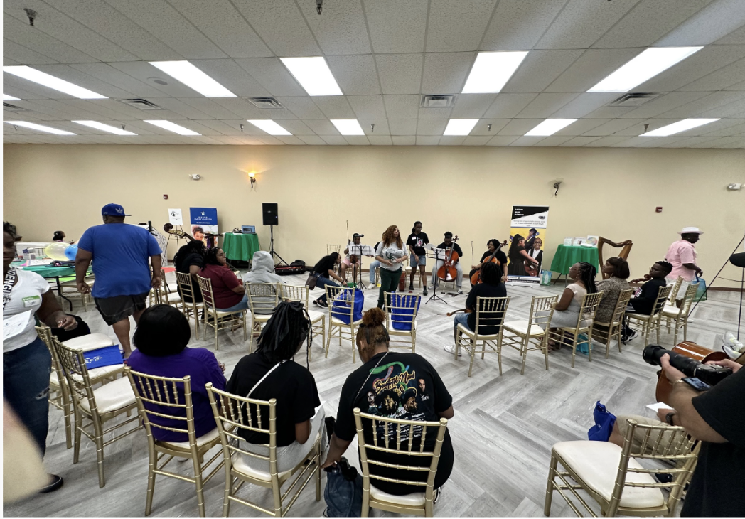 A community room with attendees seated in a circle around live musicians