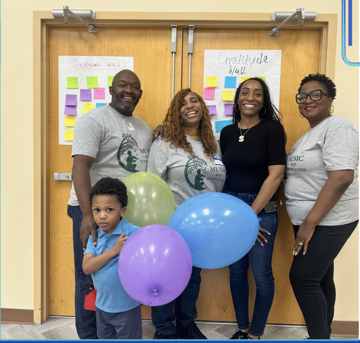 Care Solutions team and a family in front of a gratitude wall covered in sticky notes