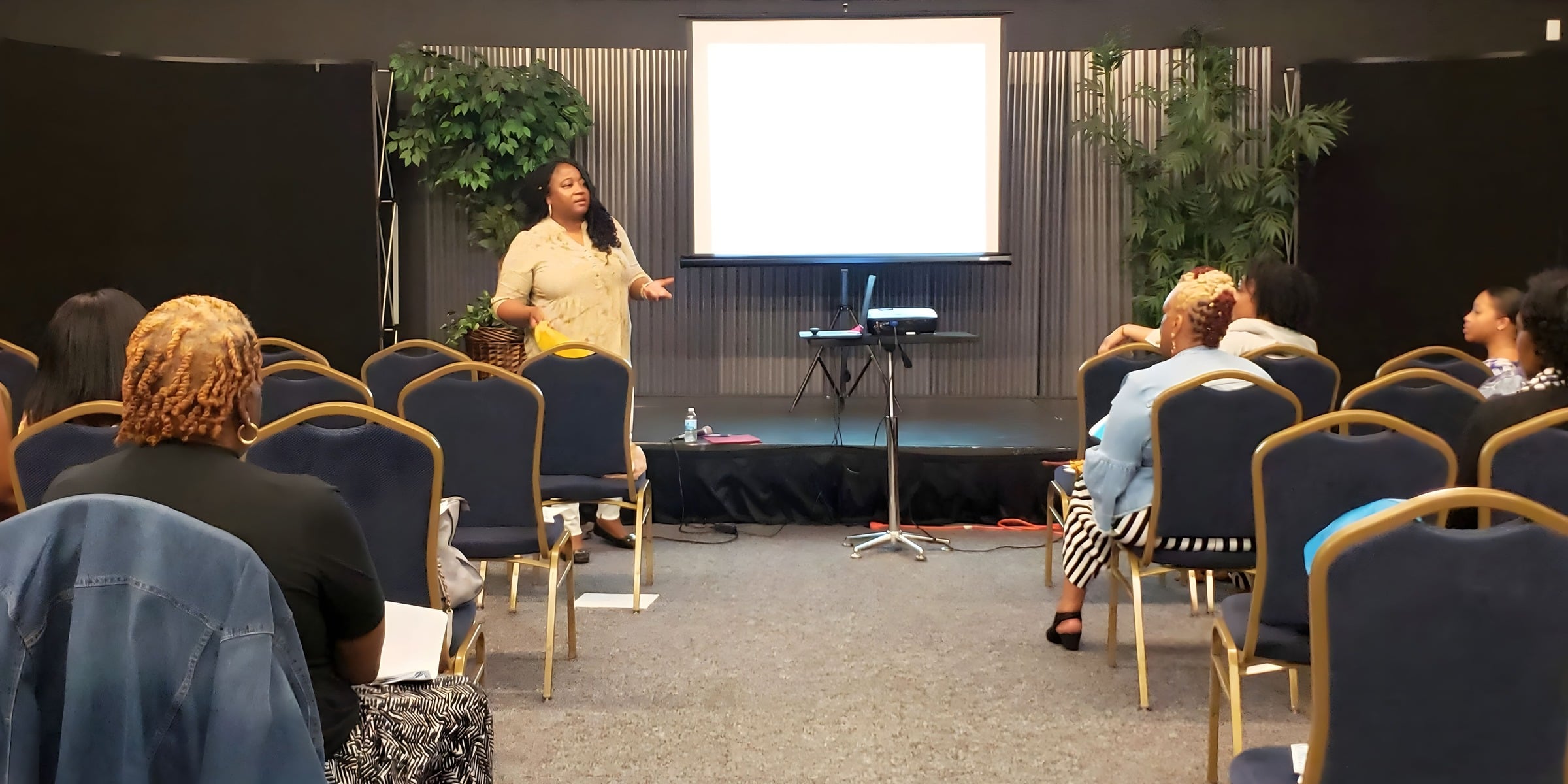 A facilitator speaks to a small audience in a community room
